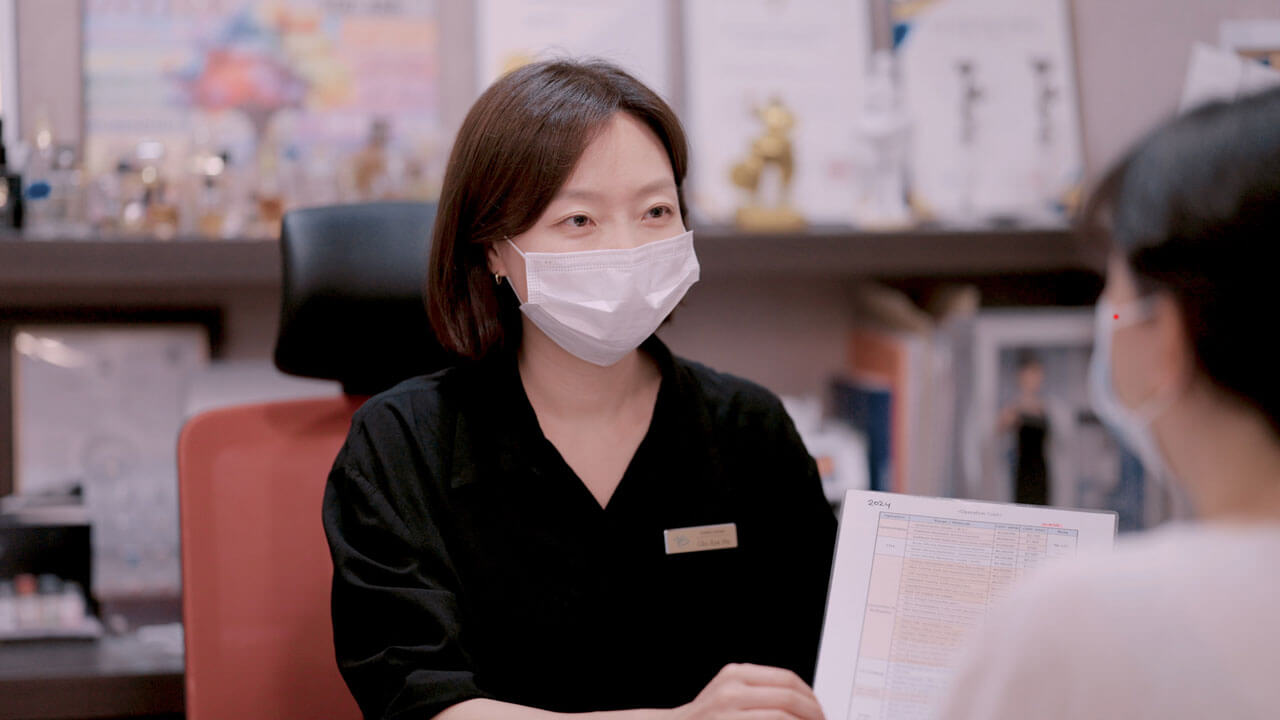 An Evita Clinic coordinator going through an English-language treatment and cost sheet with a patient in Seoul
